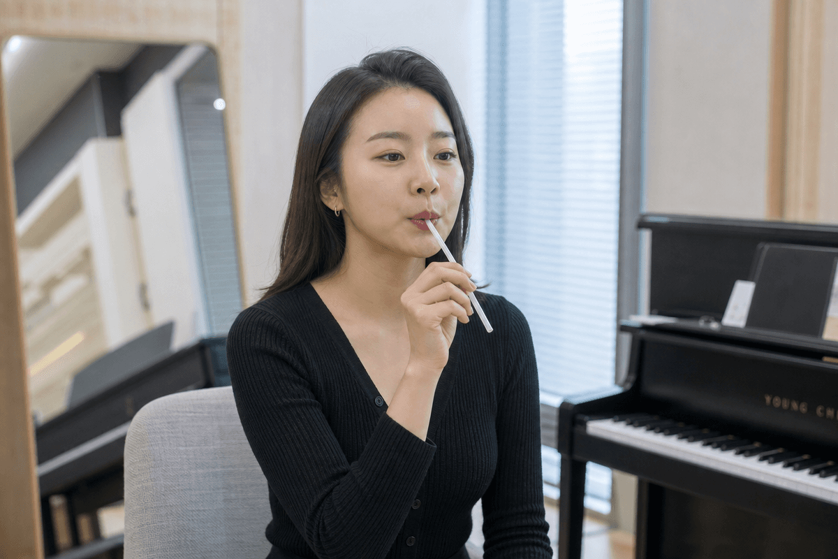 음악 교실에서 빨대를 이용해 진성 내는법 훈련을 시연하며 성대 압력 조절을 연습하는 모습