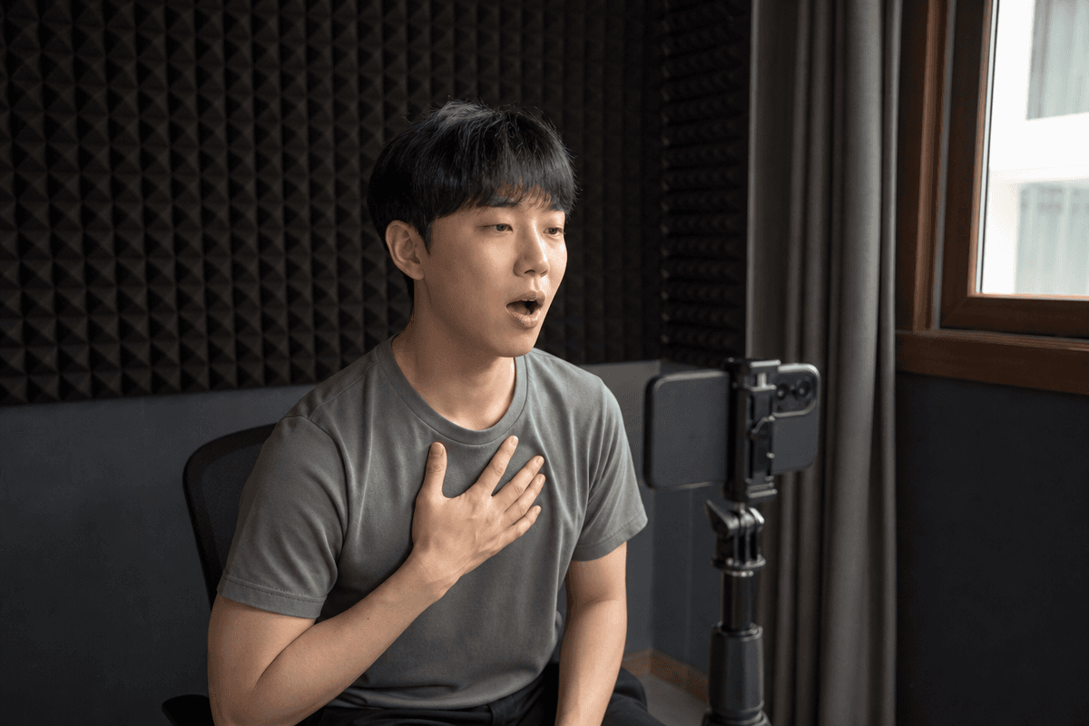 남성이 스마트폰으로 노래를 녹음하며 가슴 울림을 느끼는 장면, 진성 내는법 연습 모습