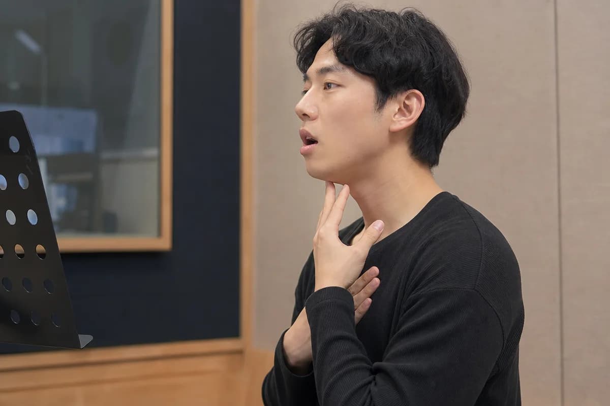 편안한 자세로 턱과 목의 긴장을 풀며 흉성 발성을 연습하는 남성