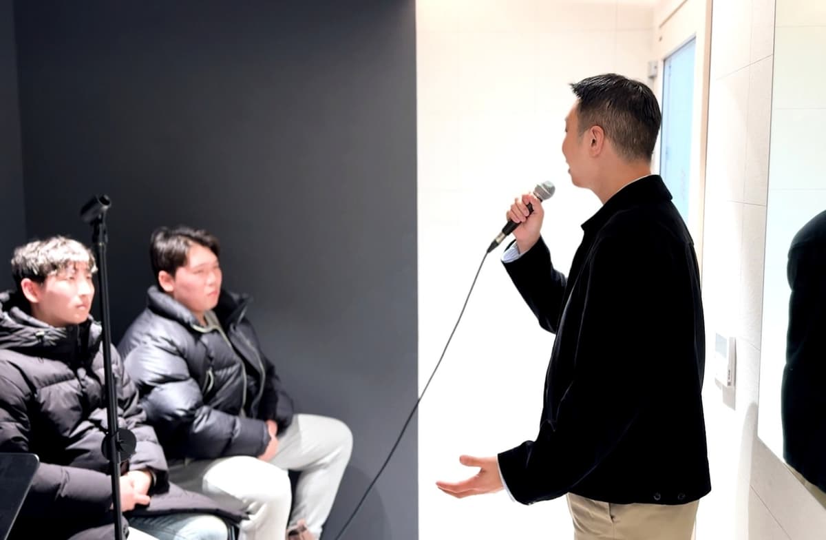 3옥타브장인 강사가 두 수강생 앞에서 마이크로 발성 시범을 보이는 소수 수업
