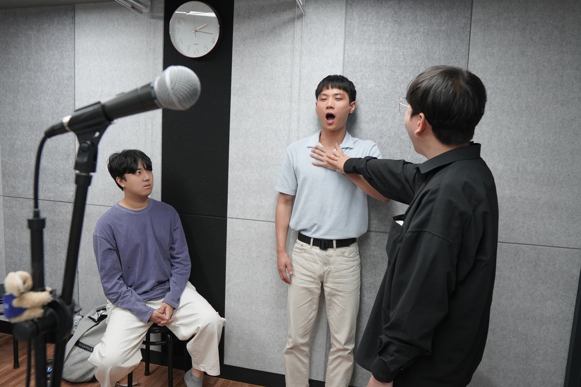 소수 그룹 보컬 수업에서 수강생의 발성을 교정하는 강사