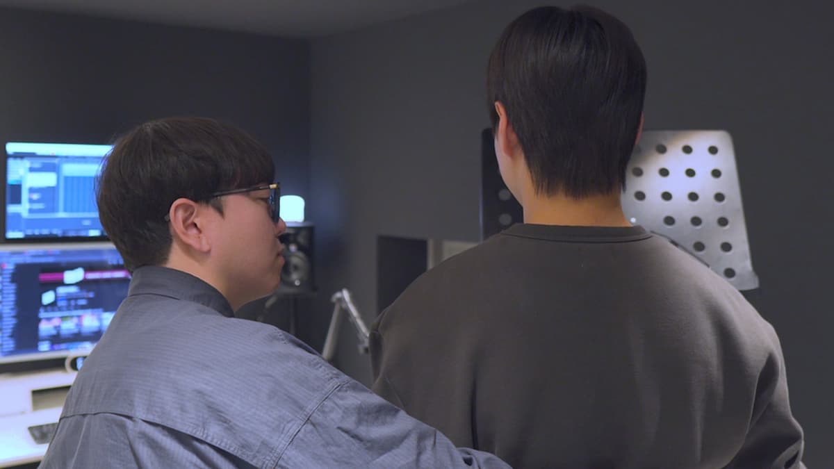 두 남성이 녹음실 모니터를 보며 피드백을 나눈다.